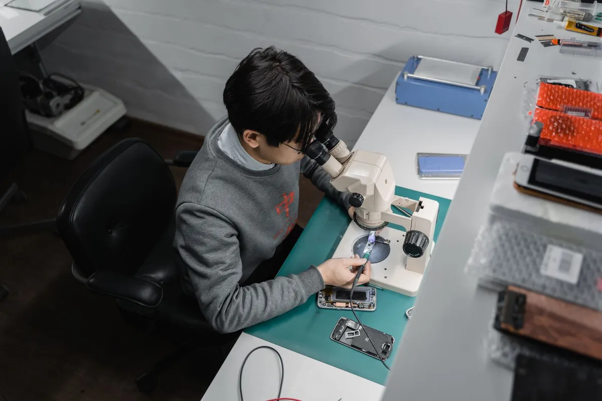 Técnico reparando un celular con microscopio